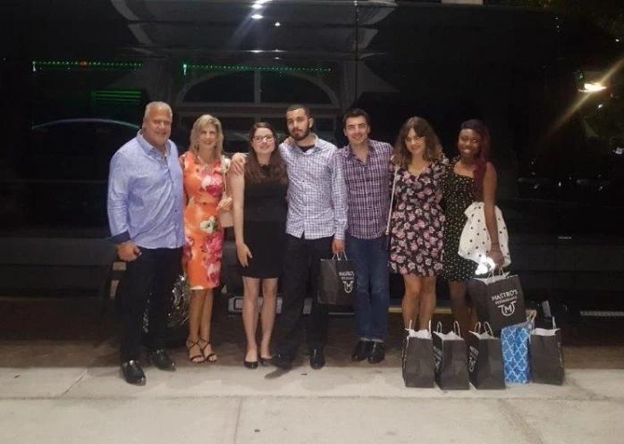 People standing near SUV limousine.